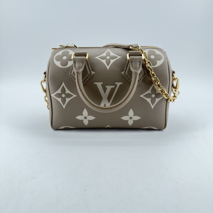 Front view of dove-gray Louis Vuitton Tourterelle Empreinte Speedy Bandoulière 20 with cream monogram print, gold hardware and chain strap
