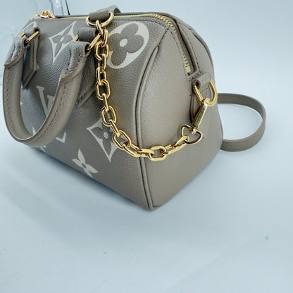 Angled view of Tourterelle Empreinte Speedy 20 with chain strap draped over the bag and leather shoulder strap