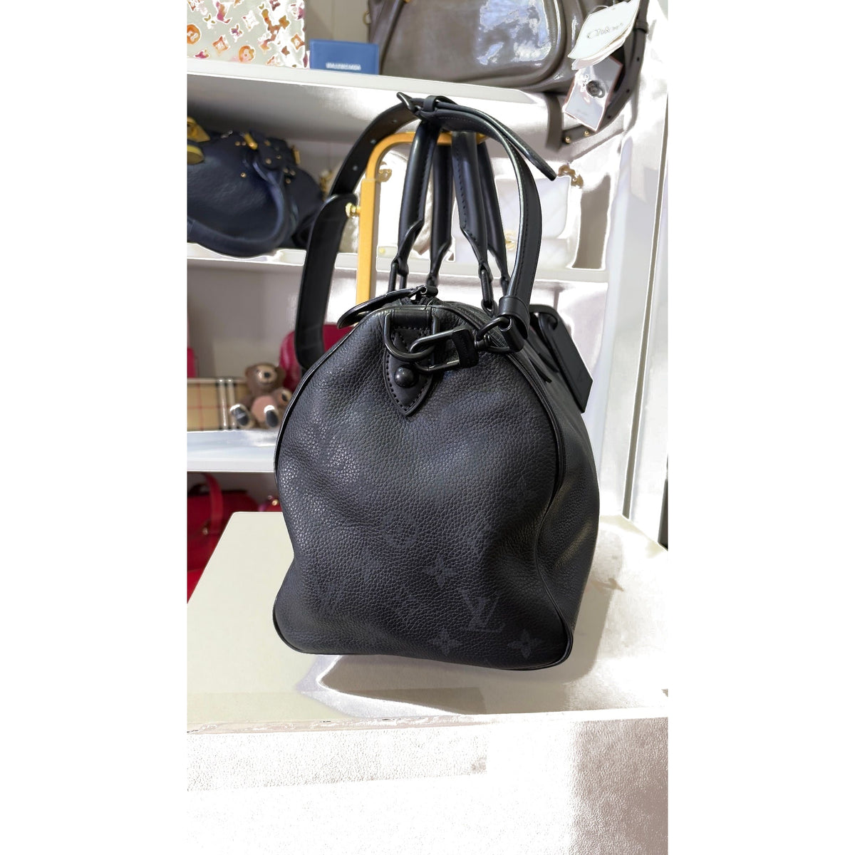 Side view showing chunky handle mounts, hardware, and detachable shoulder strap